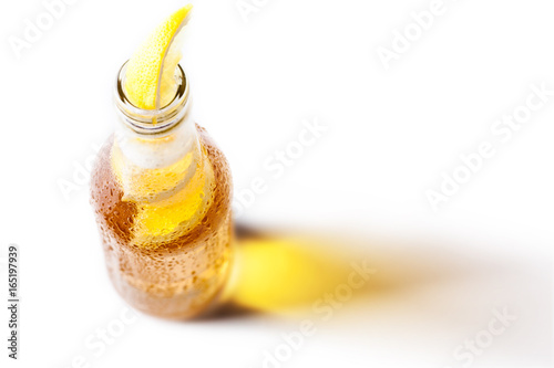 Bottle of blonde beer with lemon inside and white background