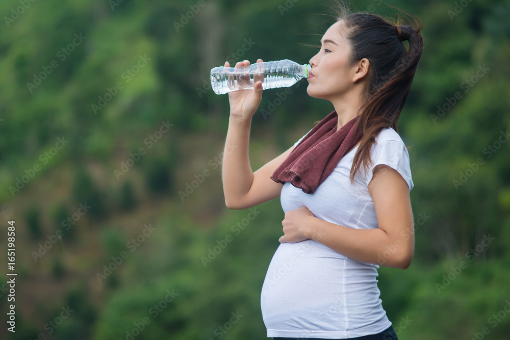 woman drinking a bottle of water on top of mountain.