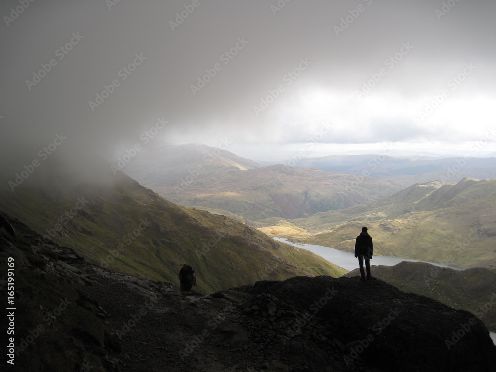 Silhouette of hiker in cloudy landscape
