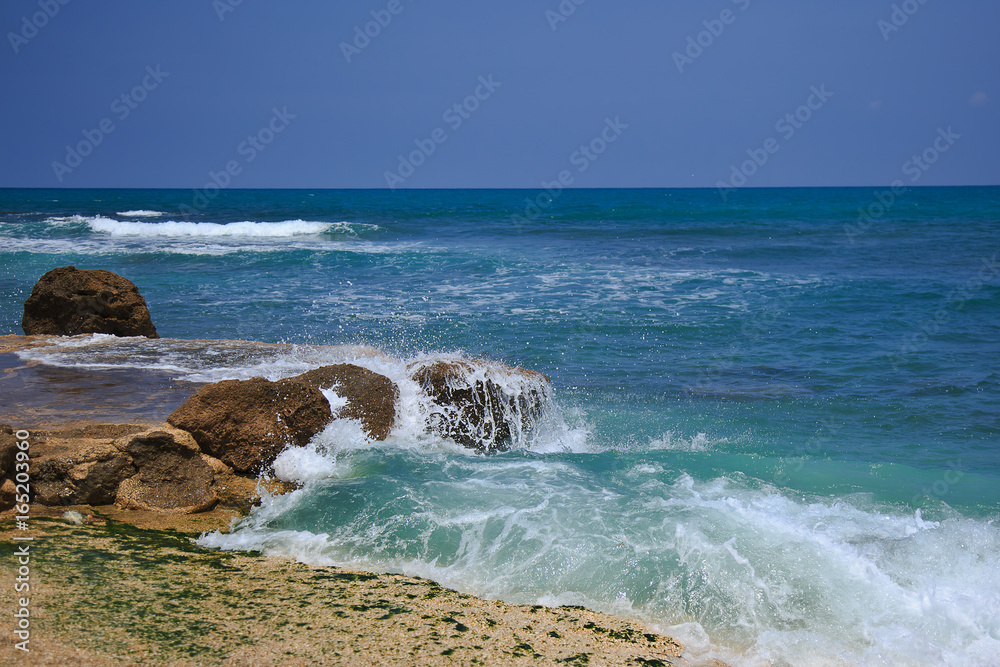 The waves breaking on a stony beach, forming a spray The waves breaking on a stony beach, forming a spray