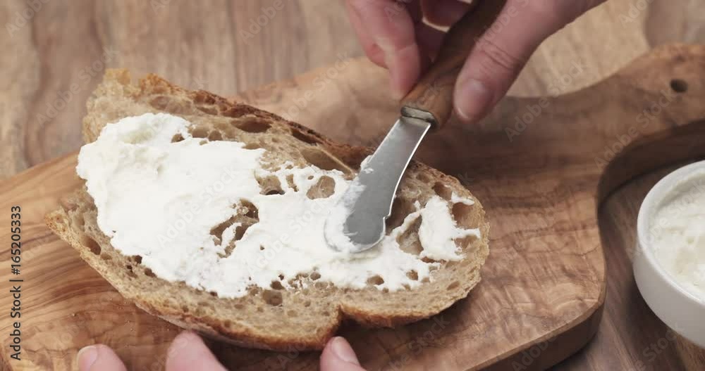 spreading ricotta cheese on fresh rustic bread