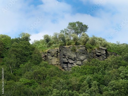 gritstone outcrop surrounded by forest in the pennine landscape near hebden bridge, west yorkshire.