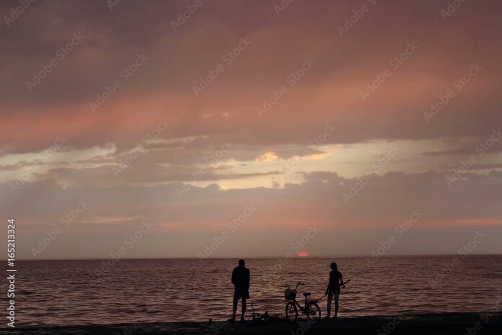 Girl and boy fishing on the sea at sunset 