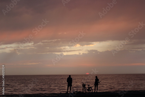 Girl and boy fishing on the sea at sunset 