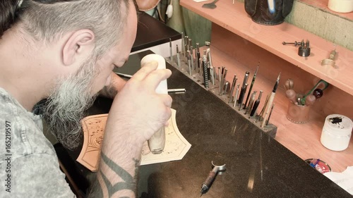 Adult tanner is engaged in embossing on a granite slab close-up 4k. photo