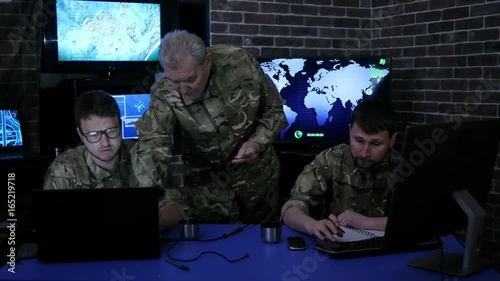security service, commander in uniform in monitoring room on war base, group military IT professionals manages station, people beside computer and monitor screen, military control