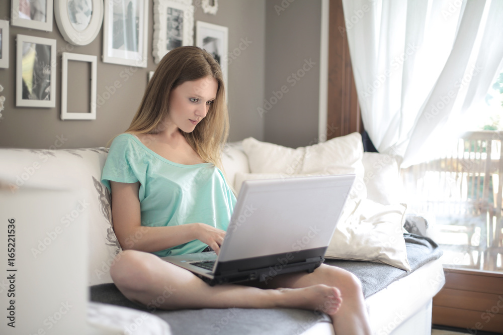 Girl sitting on a sofa, using her laptop Girl sitting on a sofa, using her laptop