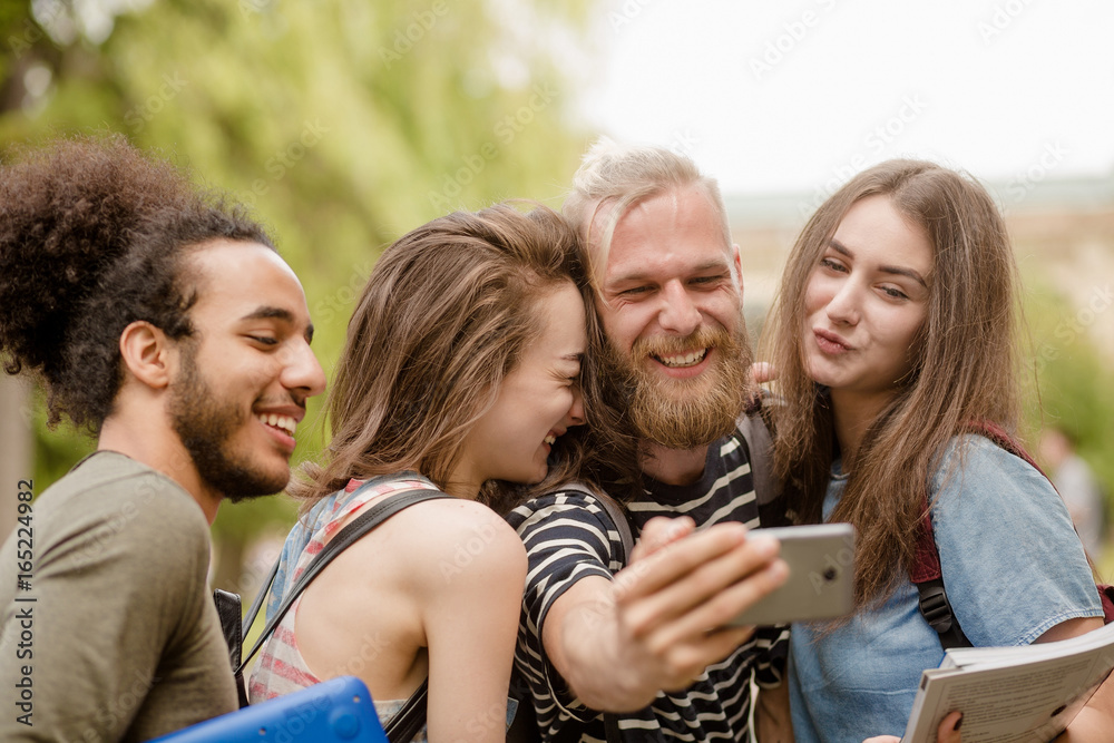 University students laughing making selfie shots. Young male and female happily smiling making photo on phone camera. University students laughing making selfie shots. Young male and female happily smiling making photo on phone camera.