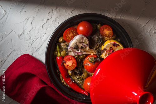 Red tazhin with vegetables, napkin on white background photo