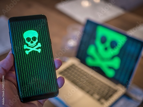 Smart phone is hacked with virus. Computer in background.