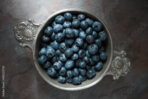 Berry bilberry in a tin bowl on a gray slate closeup