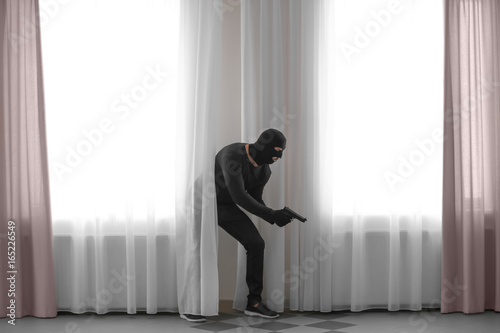 Terrorist with gun near windows with curtains in classroom. School shooting concept © Africa Studio