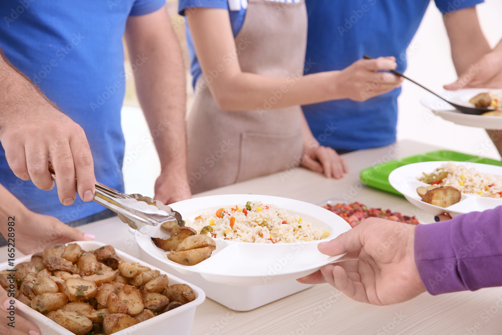 Young volunteers serving food to homeless people, closeup Young volunteers serving food to homeless people, closeup