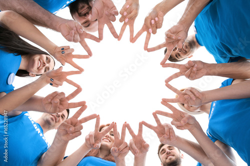 Group of young volunteers making circle with their hands on white background