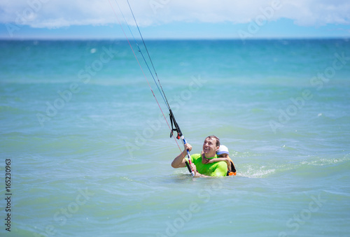 Male kite surfer showing young boy how to ride kite