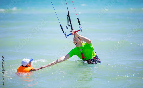Male kite surfer helping young boy to come closer