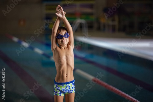 Young boy standing on side of swimming pool