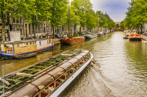 Photography Buildings and houses boats see a tourist boat pass in an amsterdam canal