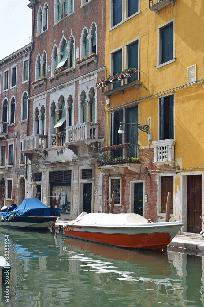 red boat docked next to a yellow building on a canal in Venice,Italy