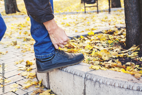 man tying shoelace in autumn park