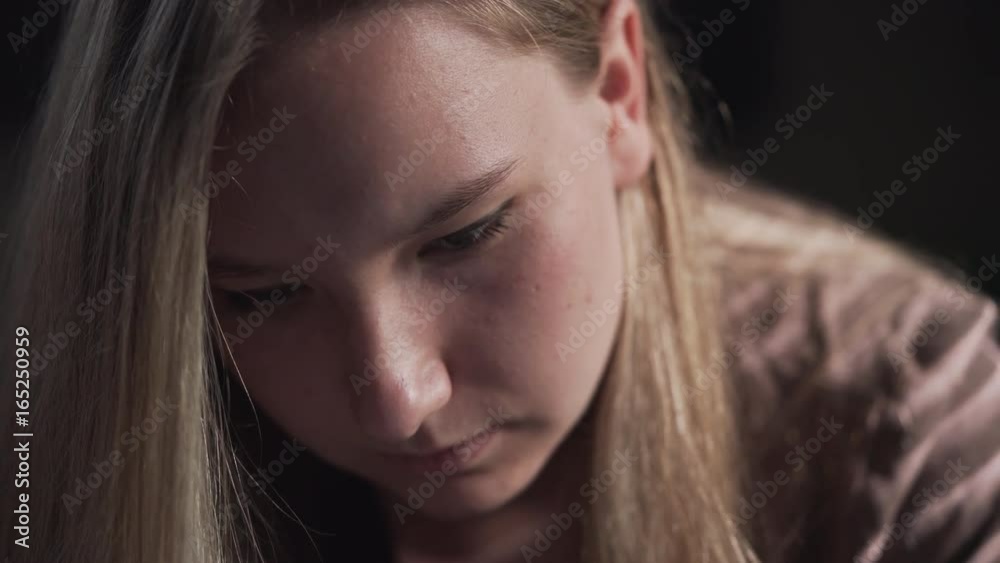 handheld closeup shot of teen girl looking at smartphone screen in sunset light near window handheld closeup shot of teen girl looking at smartphone screen in sunset light near window