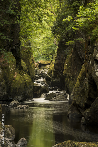 Stunning landscape with river flowing through deep sided gorge with vibrant green foliage © veneratio