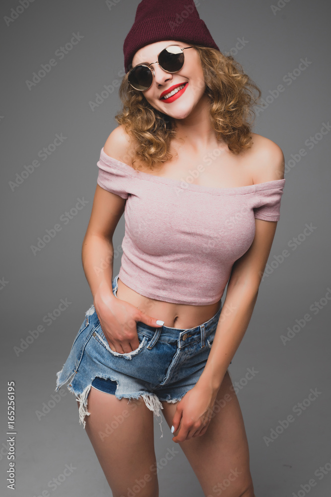 Stylish fashion portrait of trendy casual young woman in sunglasses and hat hipster in studio Stylish fashion portrait of trendy casual young woman in sunglasses and hat hipster in studio