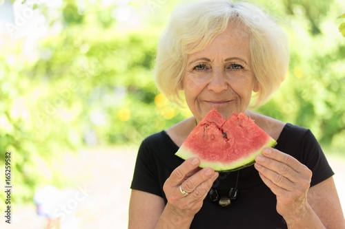 Mature woman eating watermelon.