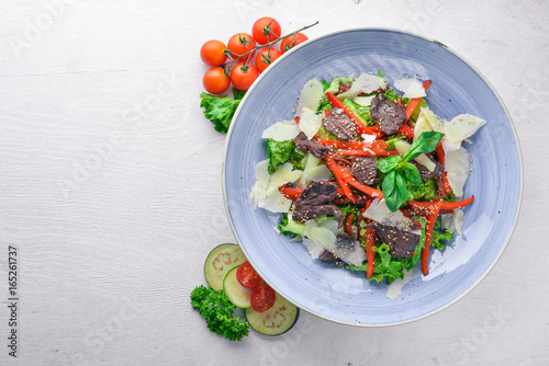 Veal and fresh vegetables salad. On a wooden background. Top view. Free space for your text.