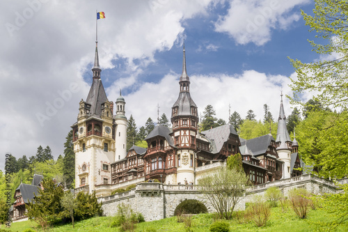 Beautiful view of the famous Peles Castle, Sinaia, Romania, with the Romanian flag flying on top of a spire
