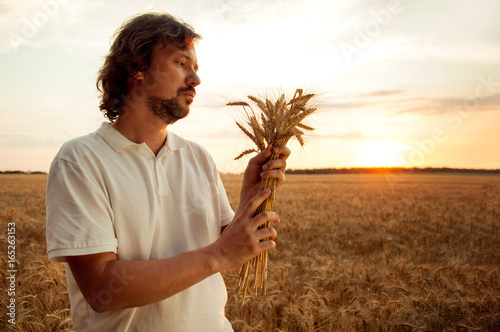 Man with wheat ears on background of field
