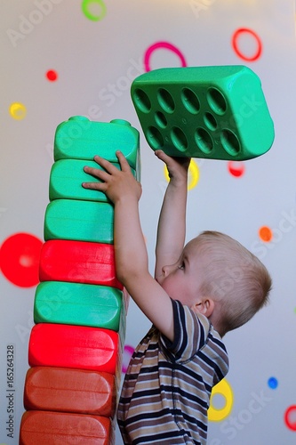 Child building a chimney from big colored cubes. Training moror skills. photo