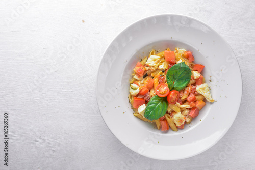 Pasta with vegetables, basil and Parmesan cheese. Italian food. On a wooden background. Top view. Free space for text.