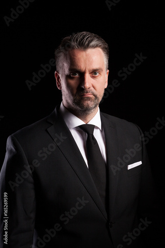 Portrait of adult confident businessman in studio photo on black background