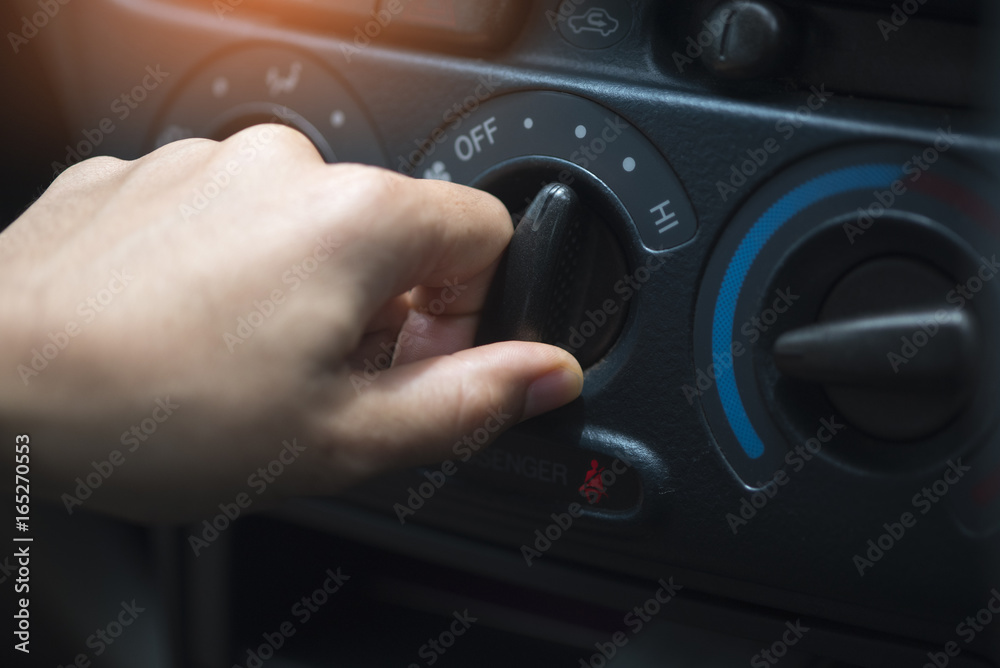 Woman hand is adjusting car air conditioning