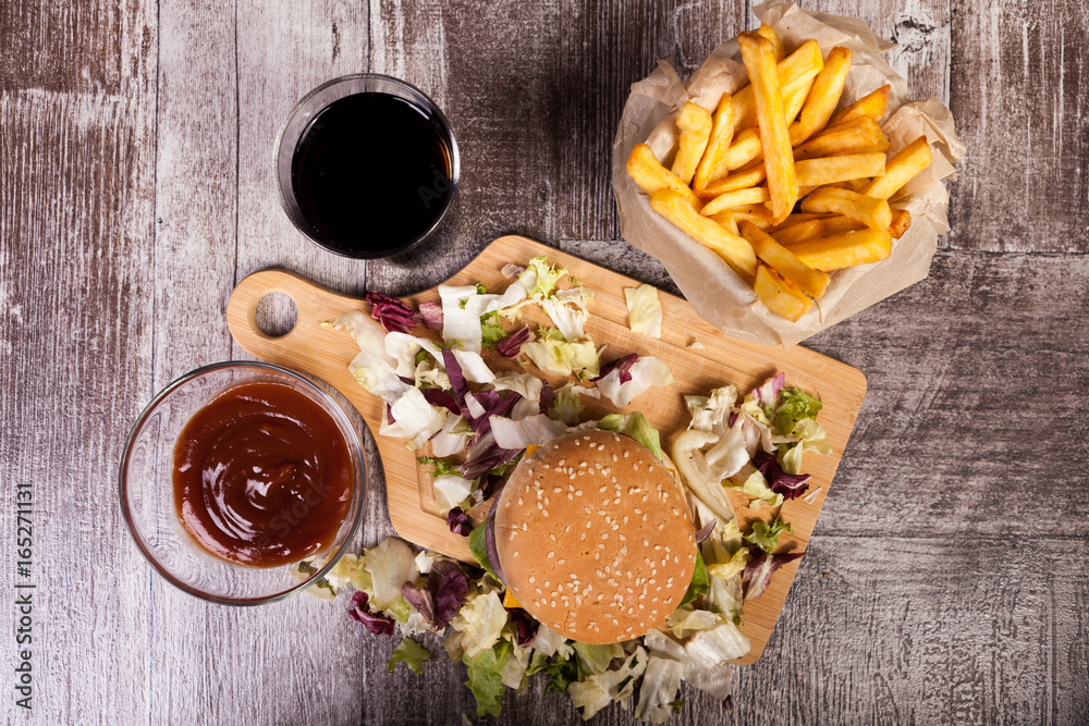 Home made burgers on wooden plate next to fries. Fast food. Unhealthy snack Home made burgers on wooden plate next to fries. Fast food. Unhealthy snack