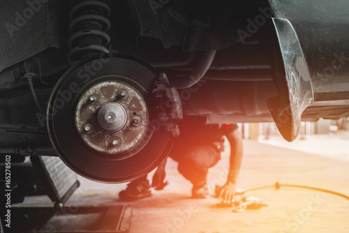 Car mechanic Repairing brakes pads on car in garage