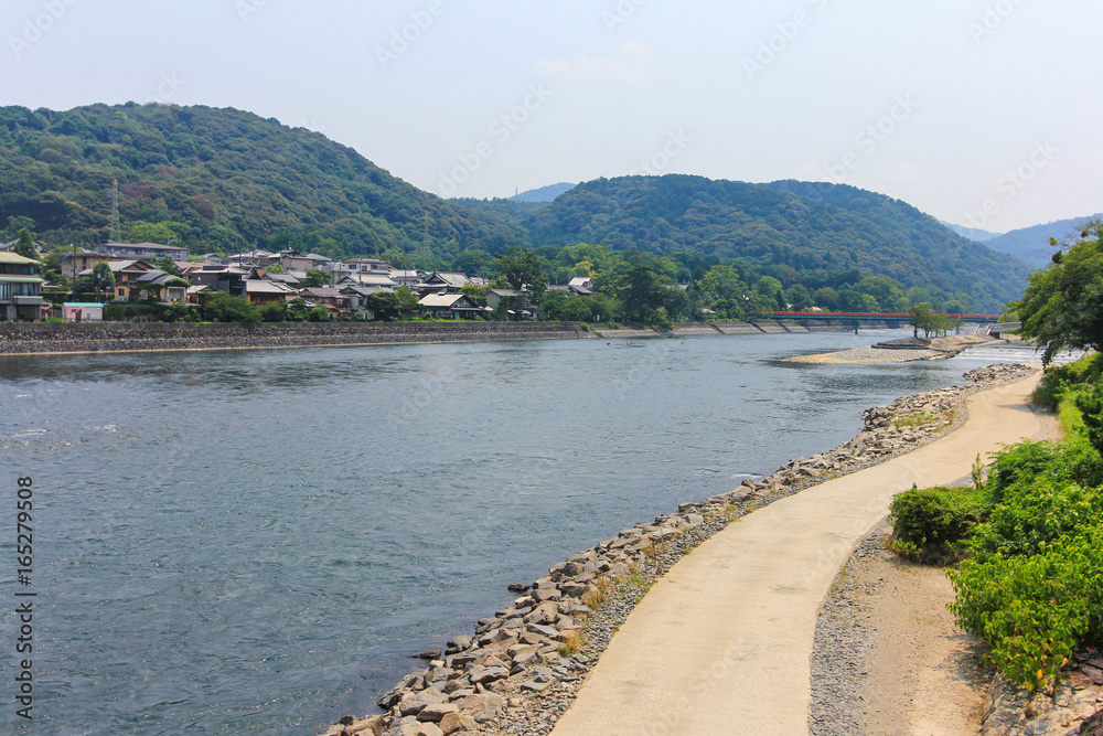 View of Uji river with the Uji Bridge, houses, mountain and blue sky in summer, at Uji city near Kyoto, Japan.