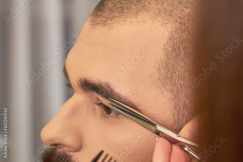 Scissors cutting eyebrow of man. Brow grooming close up.