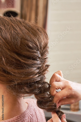 Hands of hairstyist plaiting braid. Female hairdo macro.