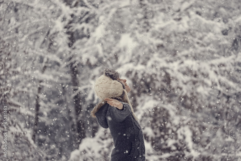 Toned image of a woman celebrating winter standing outdoors in falling snow Toned image of a woman celebrating winter standing outdoors in falling snow