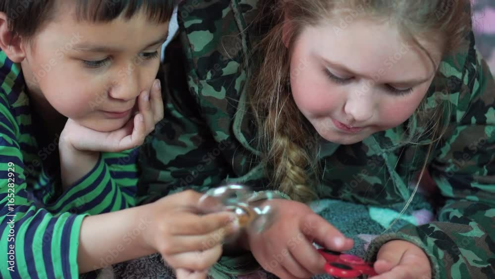 Blond Caucasian girl and a multi-ethnic boy playing at home with a Spinner toy 4K Blond Caucasian girl and a multi-ethnic boy playing at home with a Spinner toy 4K