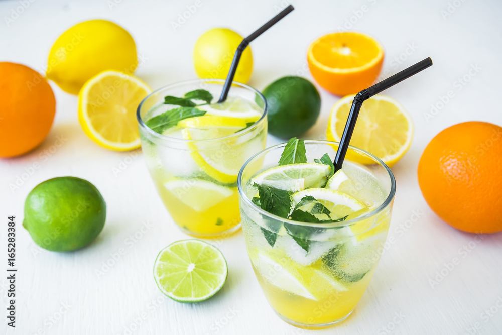 citrus lemonade with limes, mint and lemons in glasses on white table citrus lemonade with limes, mint and lemons in glasses on white table