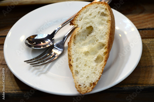 A slice of bread with spoon and fork on white plate