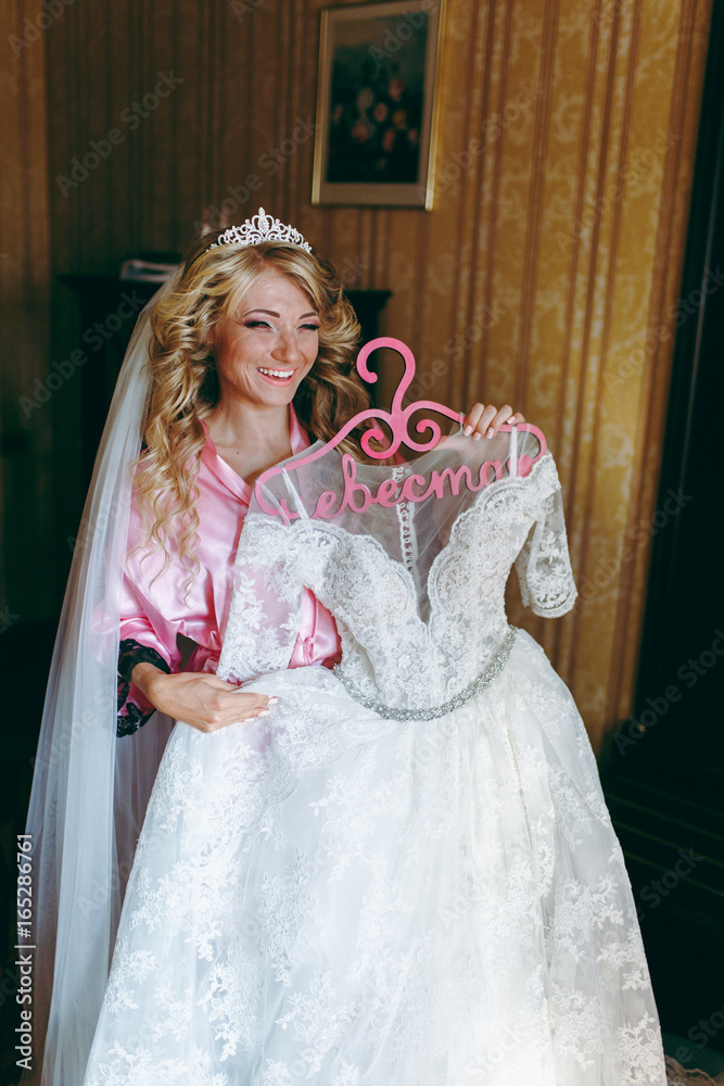 Beautiful blonde bride holding a wedding dress
