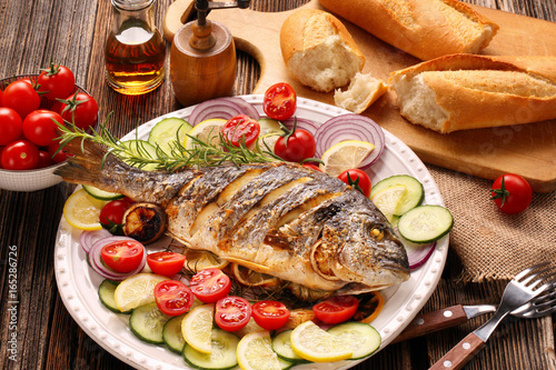 Photography Roasted dorada fish with vegetables on wooden background