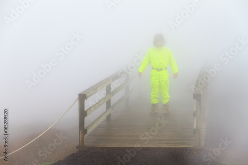 Colorful well dressed tourist coming out of the steam at the observation deck in the Gunnuhver geothermal area, Iceland