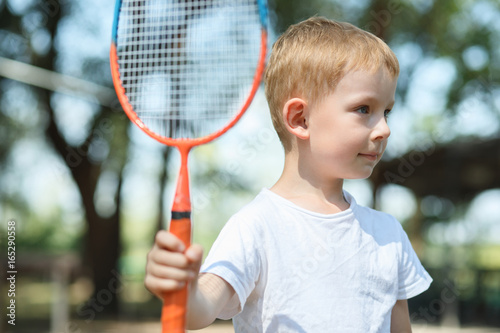 Little boy plays badminton in a pine forest, active rest at a nature