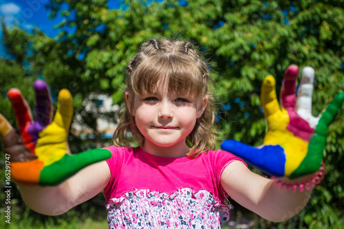 Cute girl showing her hands painted in bright colors. Art and painitng concept