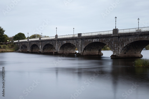 Stone bridge with arches over slow flowing river © Aidan